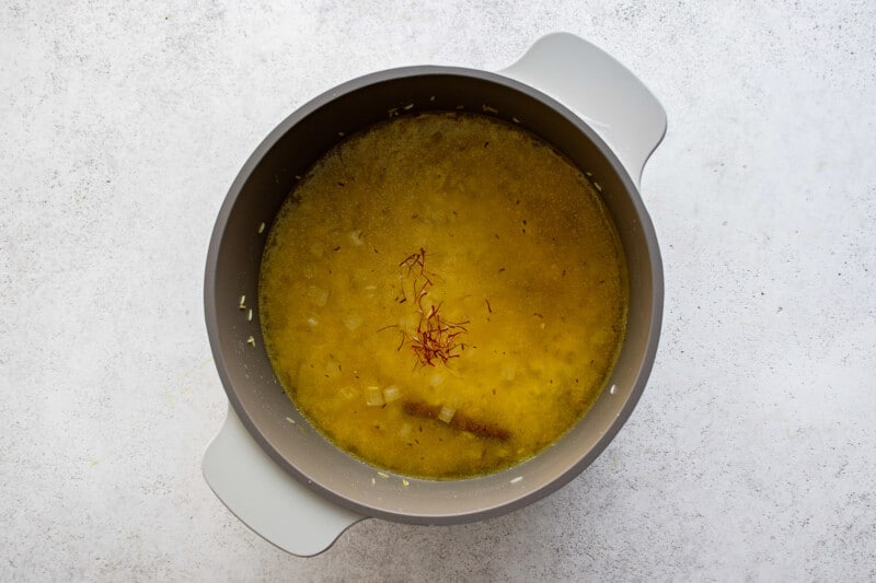 a bowl of yellow soup on a white surface.