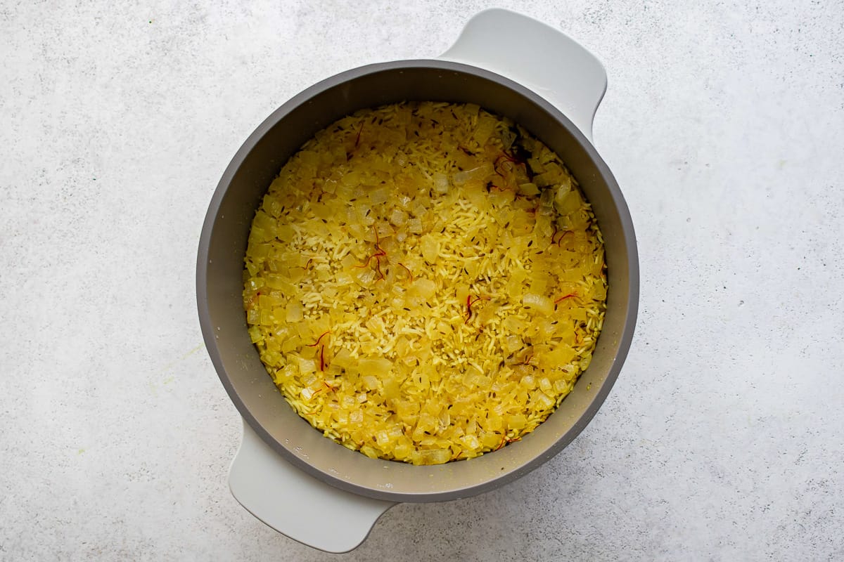 yellow rice in a bowl on a white surface.