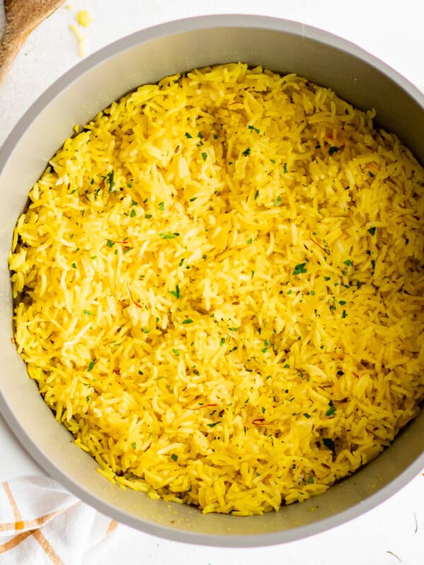 yellow rice in a pan with a wooden spoon.