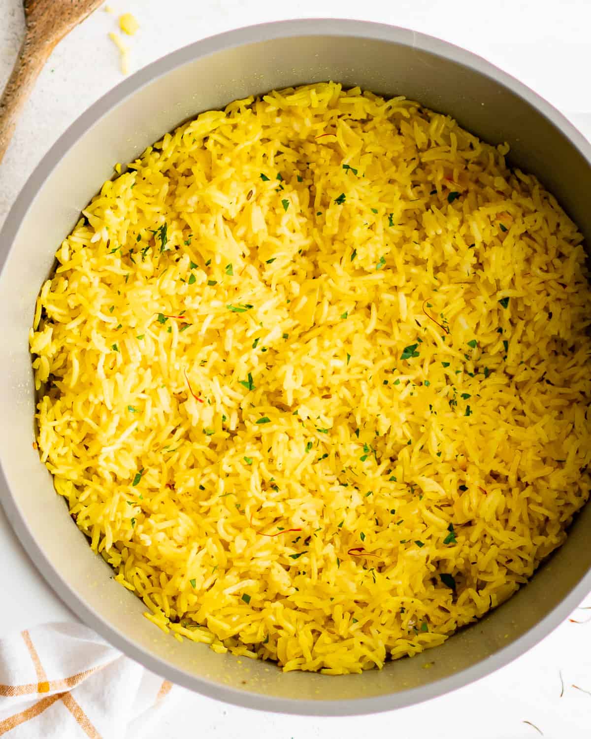 yellow saffron rice in a pan with a wooden spoon.