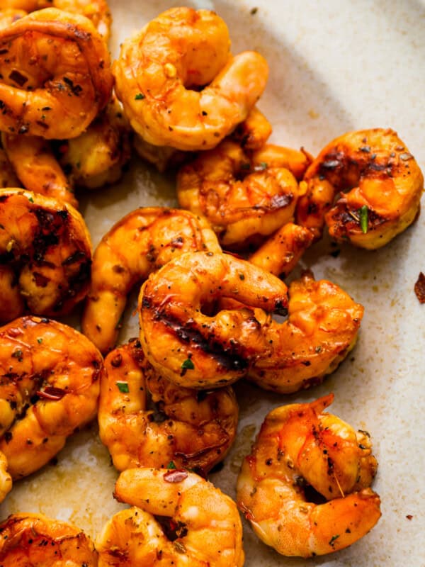 close-up overhead view of marinated grilled shrimp on a white plate.