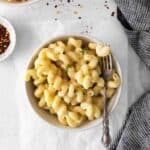 overhead view of a serving of white cheddar mac and cheese in a white bowl with a fork.