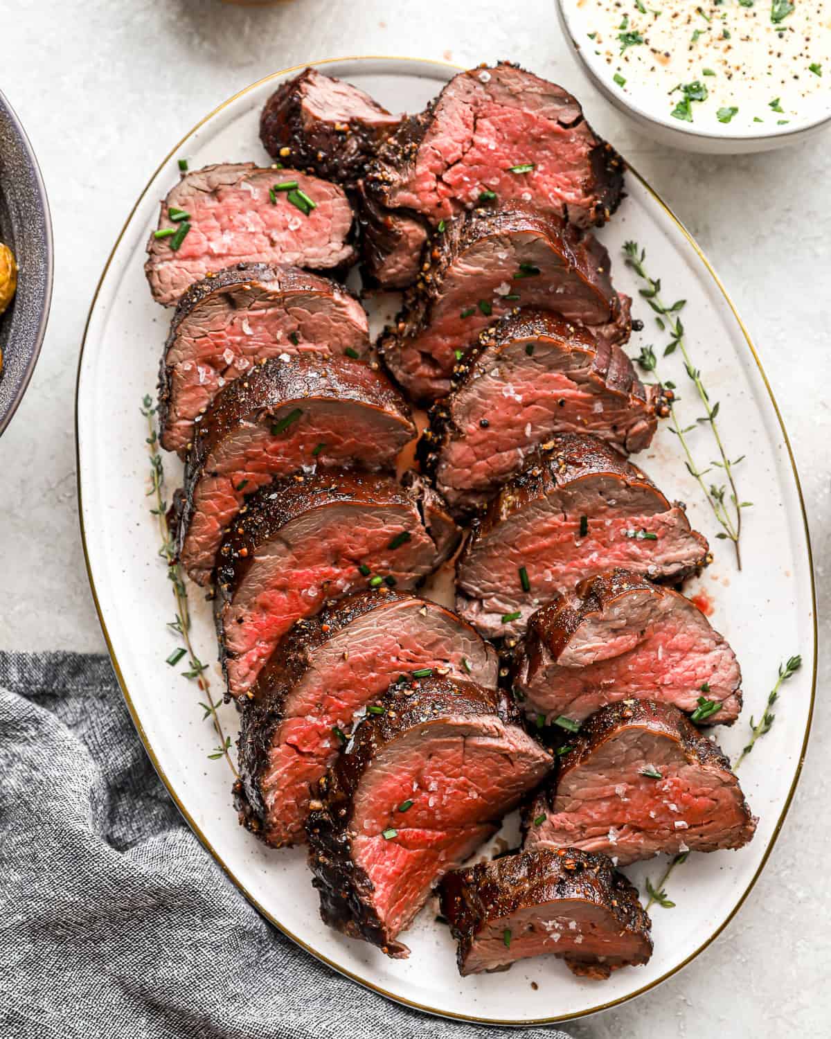 sliced beef tenderloin on a white oval plate.