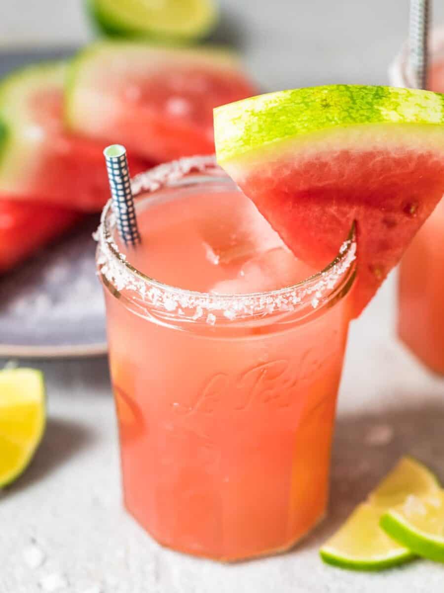 watermelon margarita with lime wedges.