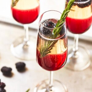 three-quarters view of 3 blackberry champagne cocktails on a metal tray.