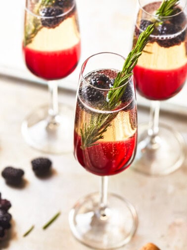 three-quarters view of 3 blackberry champagne cocktails on a metal tray.