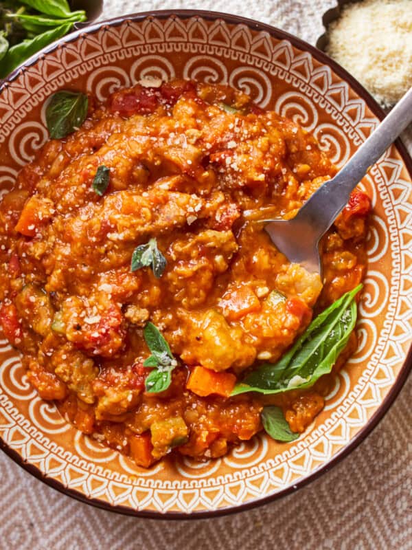 overhead view of a serving of sausage lentil soup in a patterned bowl with a spoon.