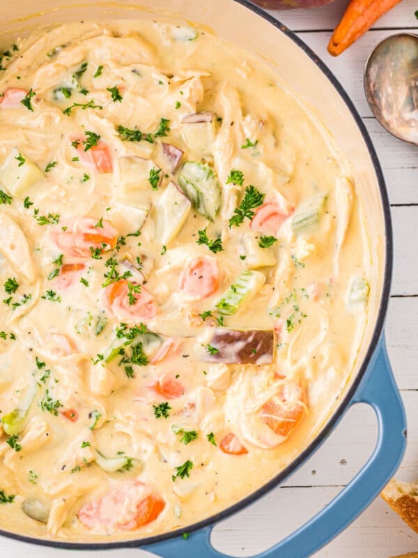 chicken chowder in a blue pot with carrots and bread.