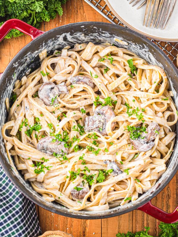 a pan of pasta with mushrooms and parsley.