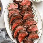 sliced beef tenderloin on a white oval plate.