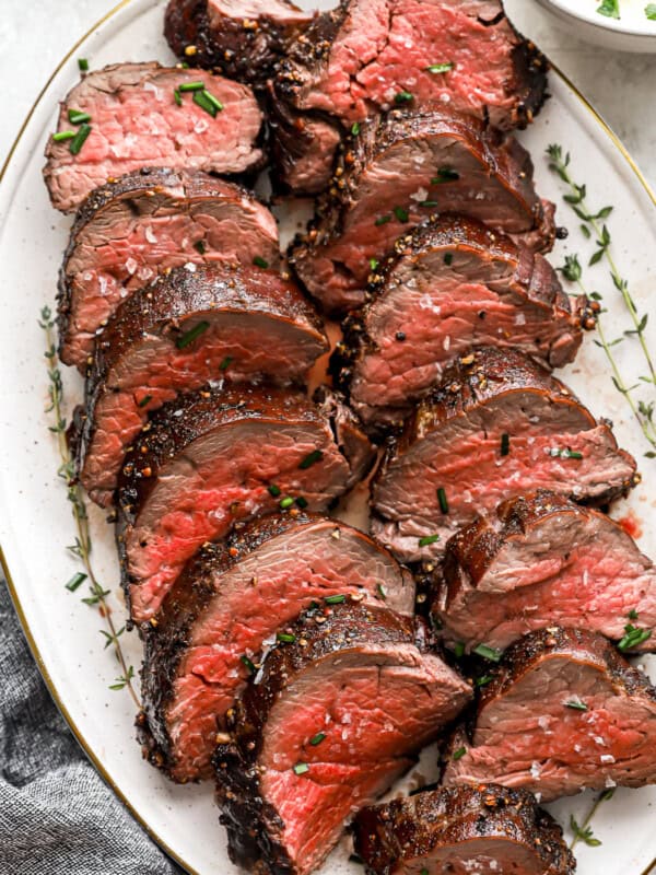 sliced beef tenderloin on a white oval plate.