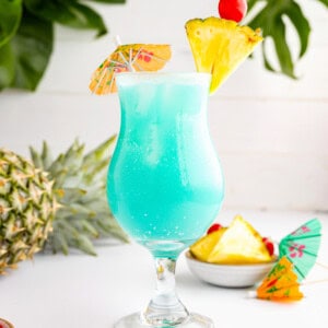 a blue hawaiian cocktail with pineapples and umbrellas.