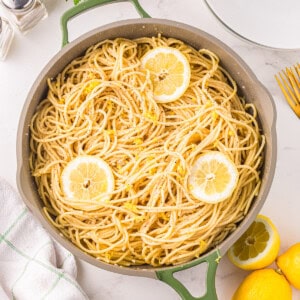 lemon spaghetti in a pan with lemon slices.