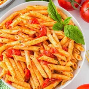 a bowl of pasta with tomatoes and basil.