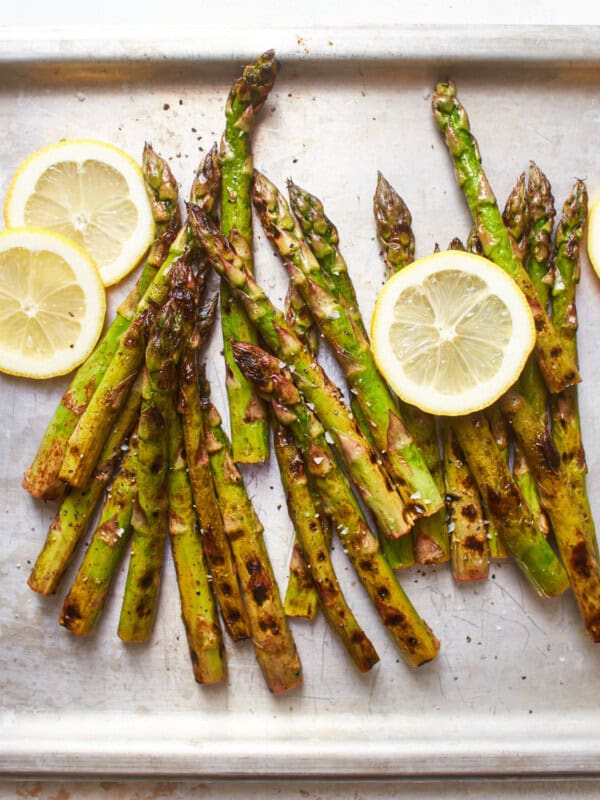 overhead view of grilled asparagus on a baking sheet with lemon wheels.