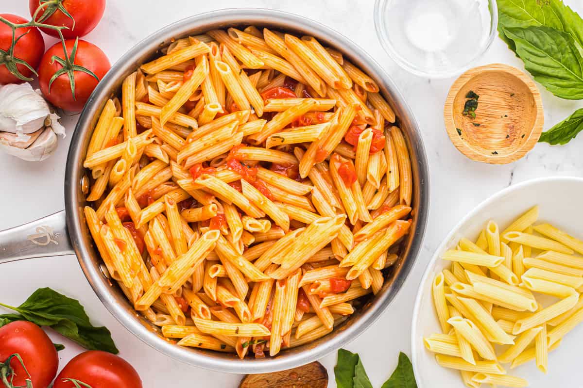 penne pasta with tomatoes and basil in a pan.