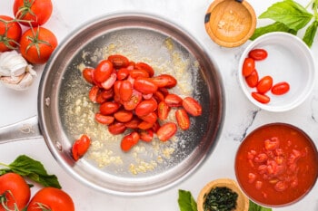 a frying pan with tomatoes, basil and garlic.