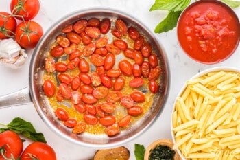 a frying pan with tomatoes, pasta and garlic.