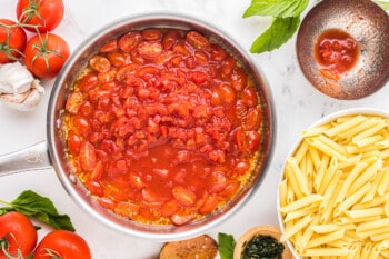 a pan with tomato sauce, pasta and other ingredients.