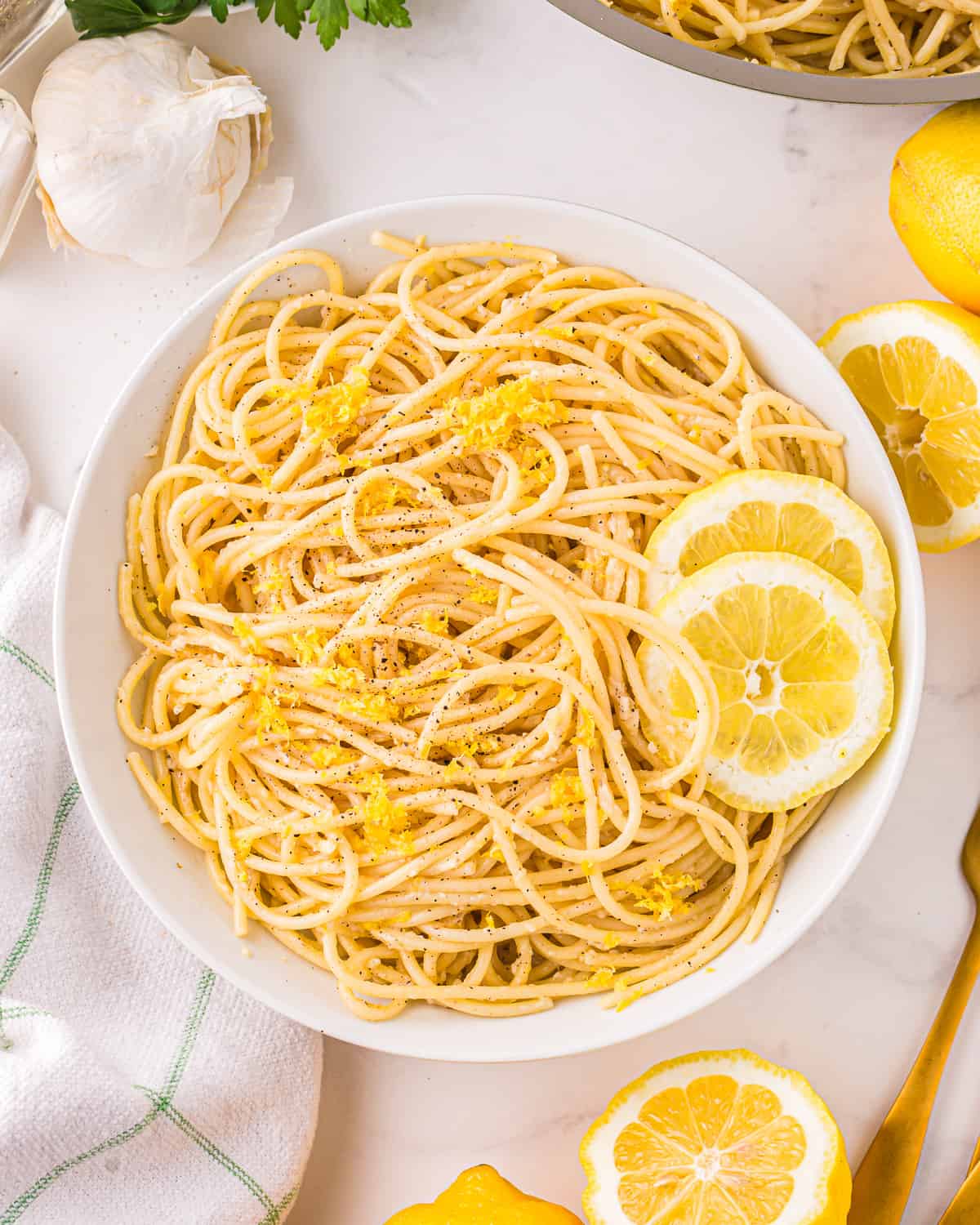 Pasta al limone in a white bowl with lemon slices.