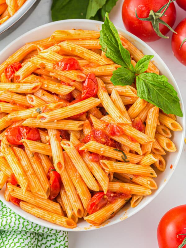 a bowl of pasta with tomatoes and basil.