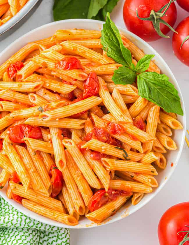 a bowl of pasta with tomatoes and basil.