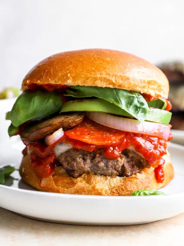 a burger on a plate with tomatoes, lettuce, and other toppings.