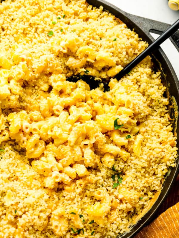 close up overhead view of smoked mac and cheese in a cast iron skillet with a serving spoon.