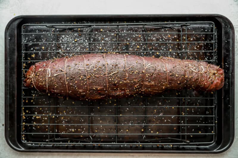 baked tied beef tenderloin on a wire rack set in a baking sheet.