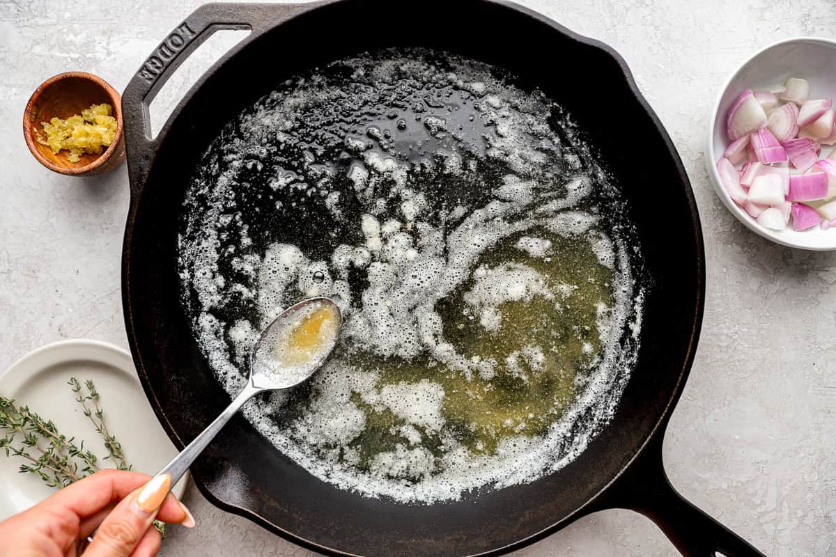 melted butter in a cast iron pan with a spoon.