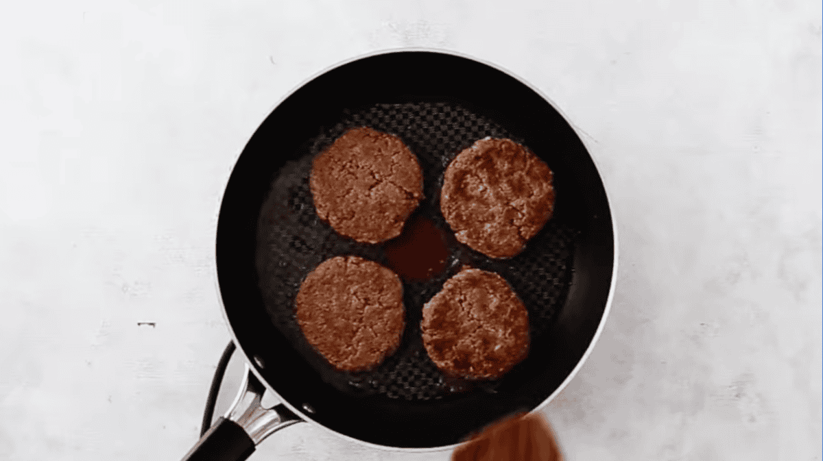turkey burger patties cooking in a pan.