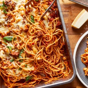 a dish of spaghetti and meatballs on a wooden table.