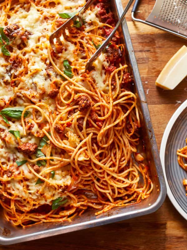 a dish of spaghetti and meatballs on a wooden table.