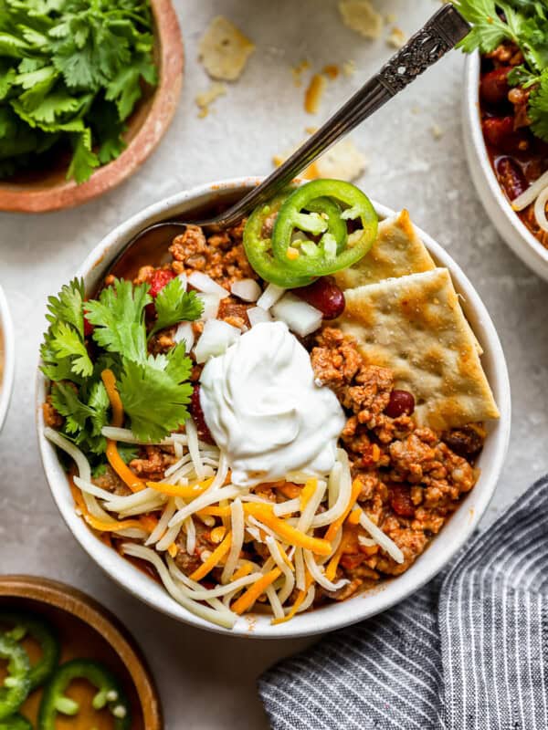 a bowl of chili with sour cream and tortilla chips.