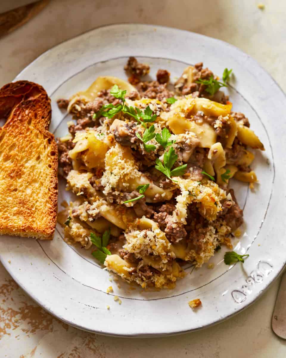 a plate of pasta with meat and bread on it.