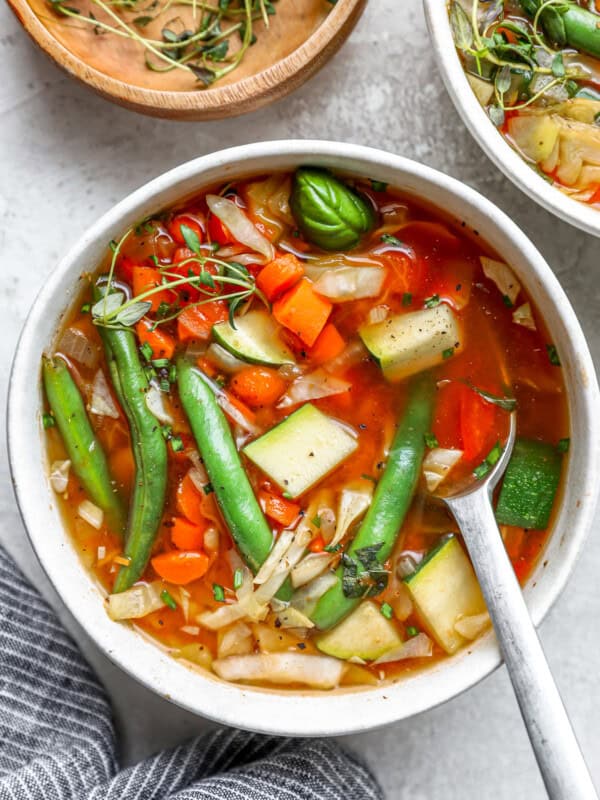 overhead view of a serving of cabbage soup in a white bowl with a spoon.