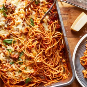 a dish of spaghetti and meatballs on a wooden table.