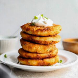 a stack of potato pancakes with sour cream and chives.