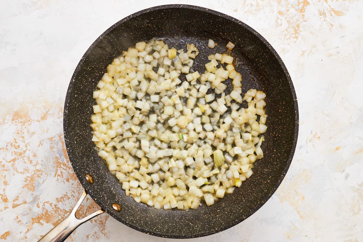 Diced onions cooking in a skillet.