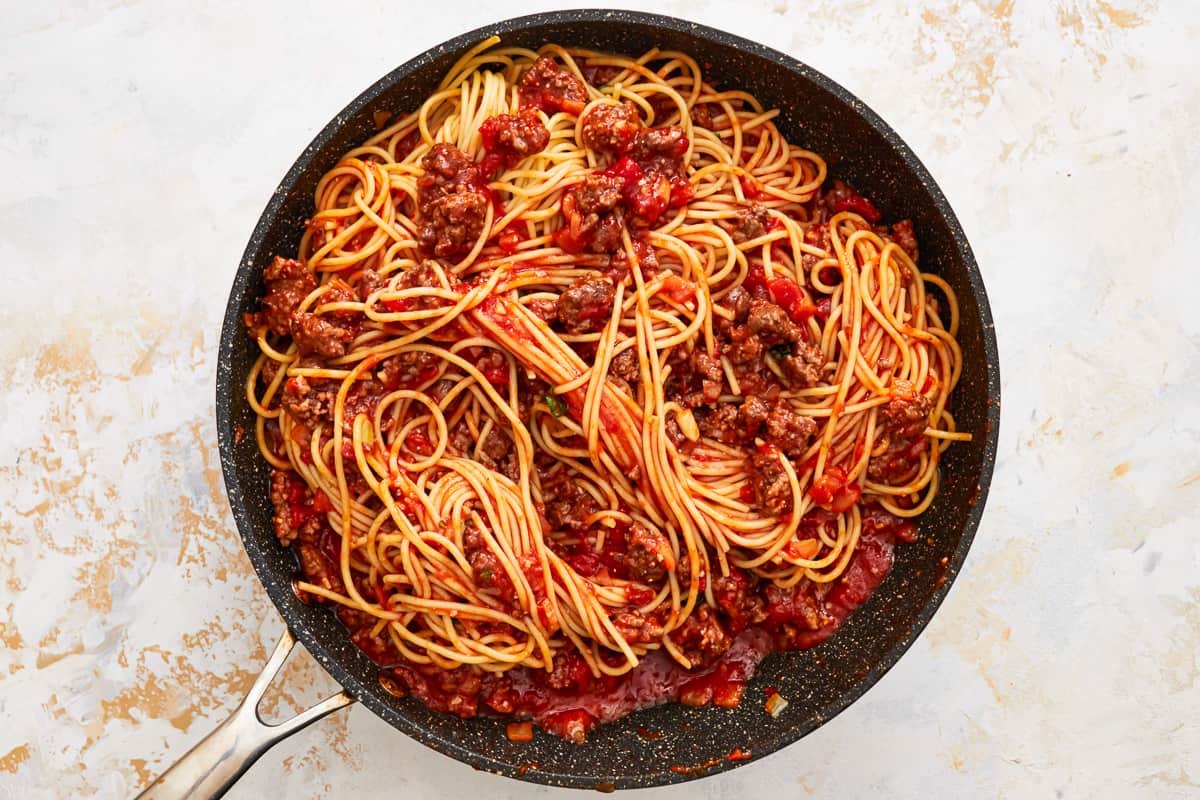 Spaghetti noodles and meat sauce combined in a skillet.