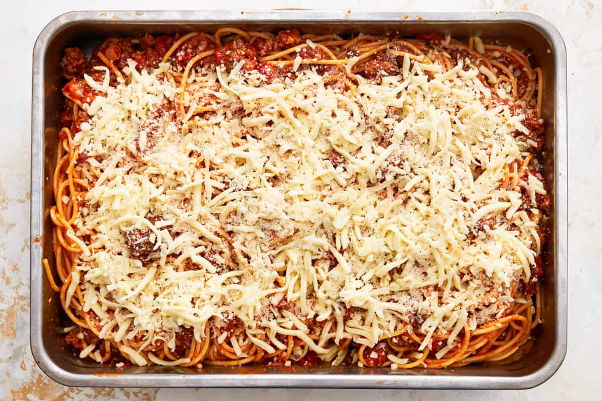 Spaghetti and meat sauce in a baking dish, topped with shredded mozzarella.