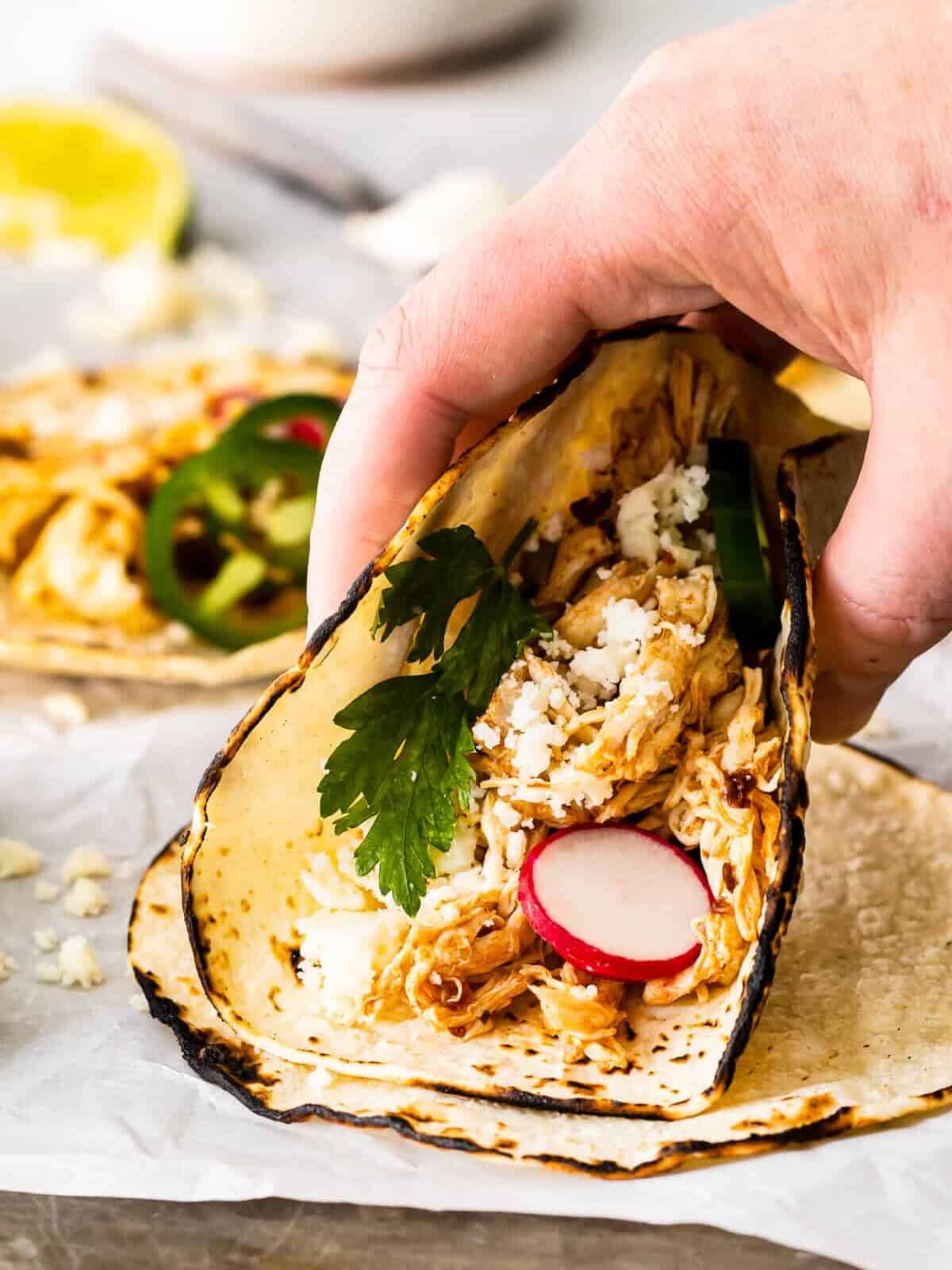 holding up instant pot shredded chicken taco