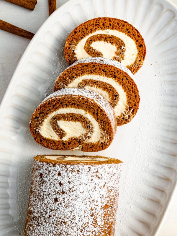 a cinnamon roll with powdered sugar on a white plate.