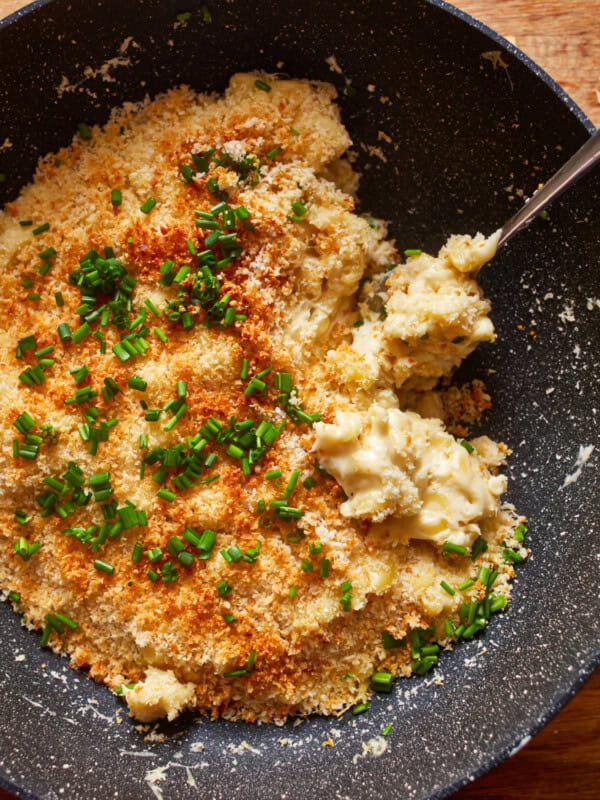 a bowl of mashed potatoes with cheese and parsley.