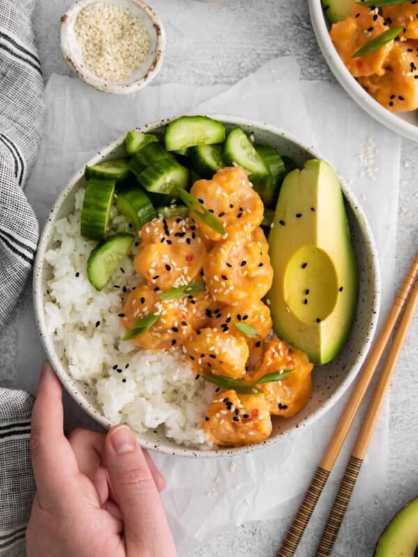 overhead view of a hand grabbing a bang bang shrimp bowl.