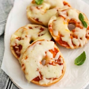 three-quarters view of 4 pizza bagels on an oval serving dish.