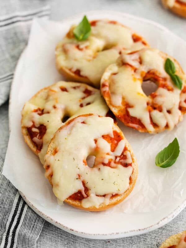 three-quarters view of 4 pizza bagels on an oval serving dish.