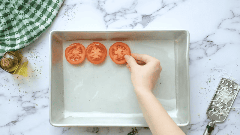 placing tomato slices on a parchment-lined baking sheet.