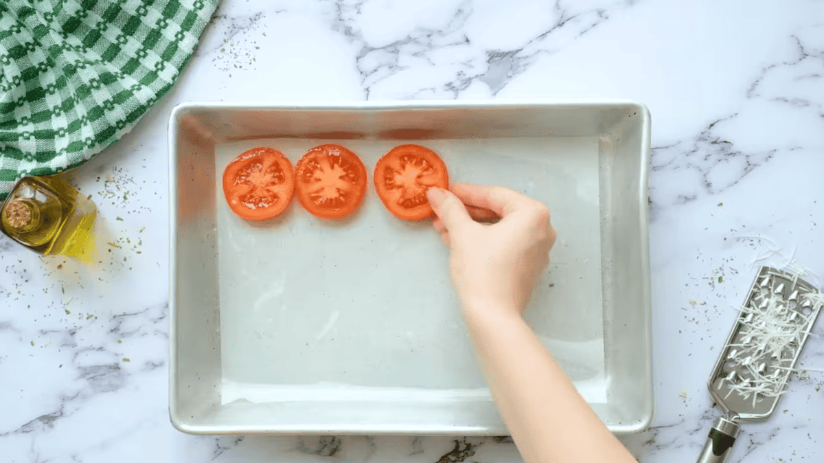 placing tomato slices on a parchment-lined baking sheet.