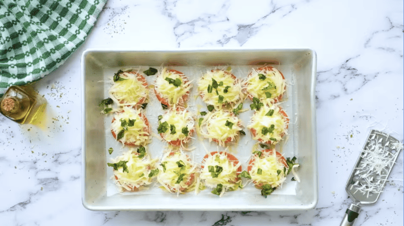 tomato slices topped with shredded cheese and basil.